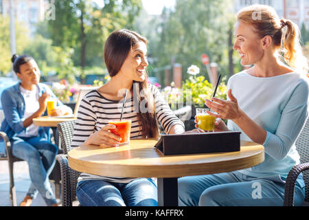 Two friends talking and drinking smoothie in cafe Stock Photo