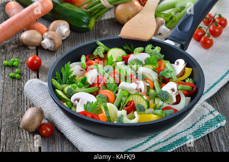 Chopped colorful vegetables in a frying pan, placed o an old linen cloth Stock Photo