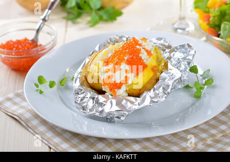Baked jacket potato with spiced cream cheese and Russian trout caviar, garnished with marjoram Stock Photo