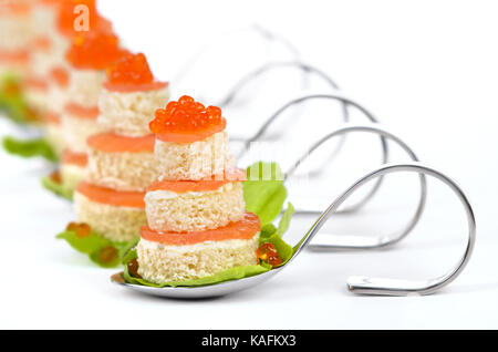 Tidbits with smoked salmon, caviar, cream cheese and toast on party spoons on white background Stock Photo