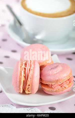 Three pink macarons with a cup of cappuccino Stock Photo