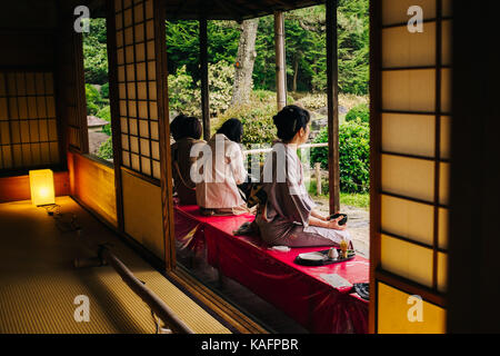 every day Street scene in Japan. Japanese women in traditional Kimono drinking tea Stock Photo