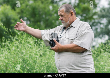 Portrait of a bearded senior photographer man with old camera gesticulating while working outdoor Stock Photo
