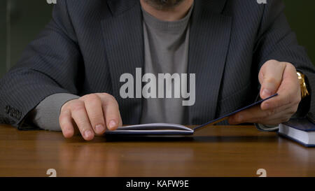 Teacher sits at the table with the record book Stock Photo
