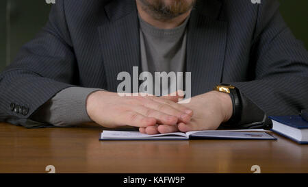 Teacher sits at the table with the record book Stock Photo