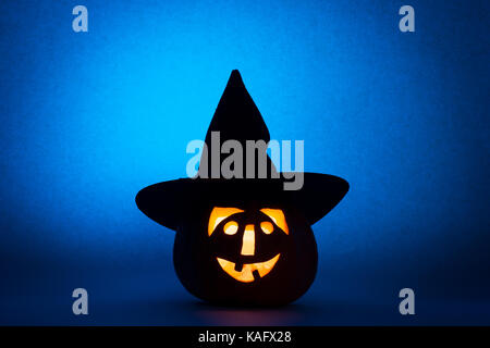 Happy Halloween pumpkin in hat, funny face on blue background. Stock Photo