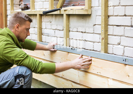 construction worker checking level of new house wood facade Stock Photo