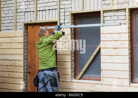 worker restoring old brick house facade with new wooden planks Stock Photo