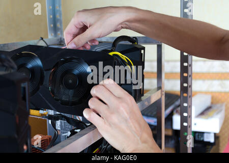 The hands install a graphics card into computer for Bitcoin mining, ethereum and other altcoins. Stock Photo