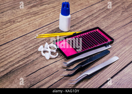 Eyelash Extension tools on wooden background. Accessories for eyelash extensions. Artificial lashes. Close up. Stock Photo