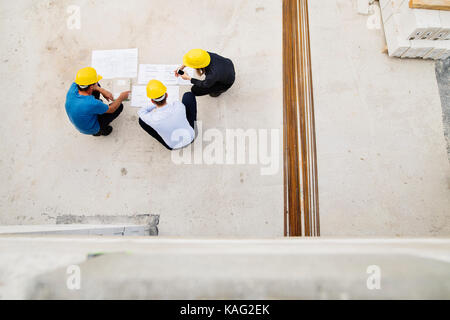 Architects and worker at the construction site. Stock Photo
