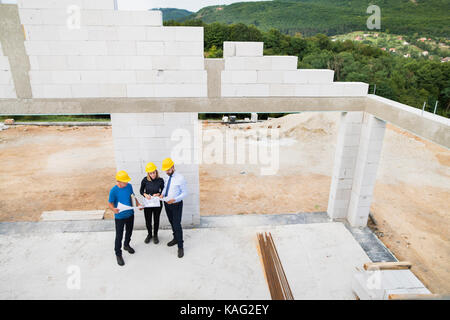 Architects and worker at the construction site. Stock Photo
