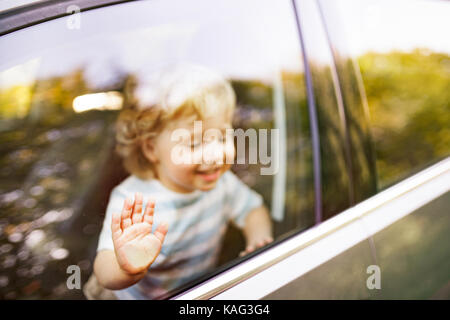 Little boy in the car, looking out of window, waving. Stock Photo