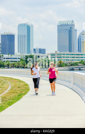 Two women jogging along Bayshore Boulevard with the downtown Tampa, Florida, USA skyline in the background. Stock Photo