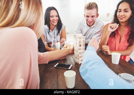Group of creative friends sitting at wooden table. People having fun while playing board game Stock Photo