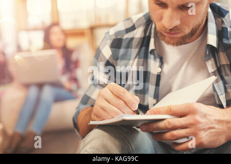 Scaled up look on serious guy making notes Stock Photo