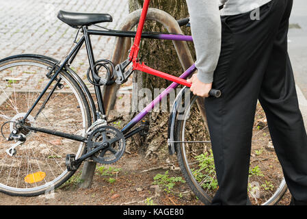 Thief Trying To Break The Bicycle Lock With Long Pliers Stock Photo