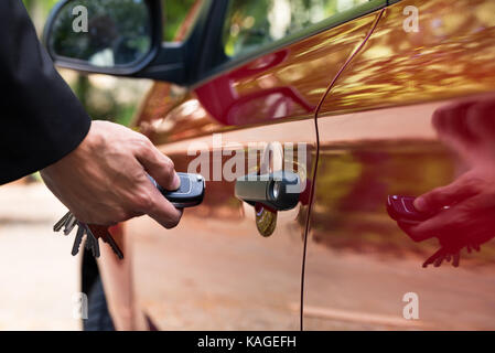 Close-up Of A Person's Hand Holding A Car's Remote Control Pointing To The Door Stock Photo