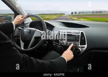 Close-up Of A Businessman Pressing Button On Dashboard While Driving Car Stock Photo