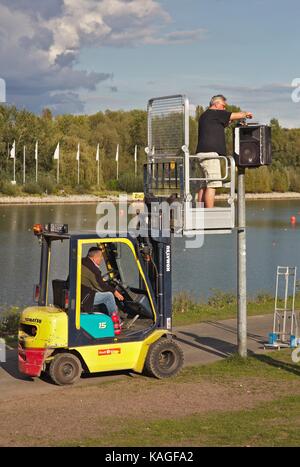 Man standing on forklift dismounting loudspeakers Stock Photo