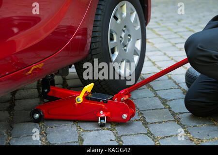 Car Lifted With Red Hydraulic Floor Jack For Repairing Stock Photo