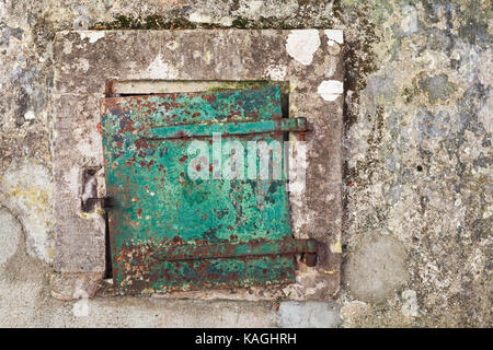 Grungy green metal door in gray concrete wall, background photo texture Stock Photo