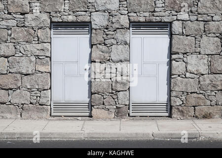 Two gray metal doors in gray stone wall. Background photo texture Stock Photo