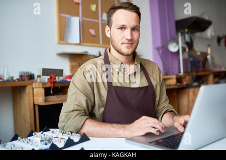 Young Man Using Laptop in Jewelry Workshop Stock Photo