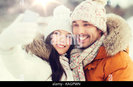 happy couple taking selfie by smartphone in winter Stock Photo