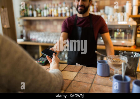 man with payment terminal and hand with smartphone Stock Photo