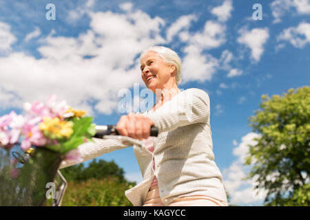 happy senior woman riding bicycle at summer park Stock Photo