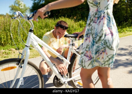 happy young couple fixing bicycle on country road Stock Photo