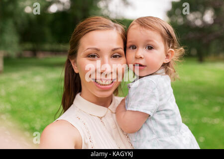 mother with baby girl taking selfie at summer park Stock Photo