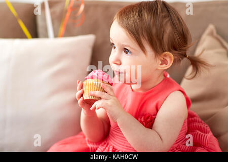 happy baby girl eating cupcake on birthday party Stock Photo