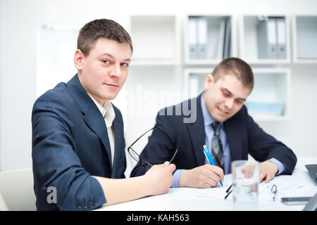 Two young businessmen signing contracts in office Stock Photo