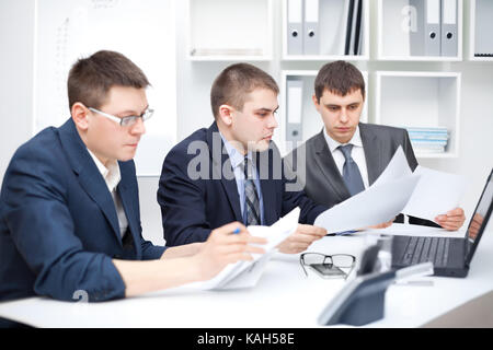 Team of young business men doing some paperwork together at office Stock Photo