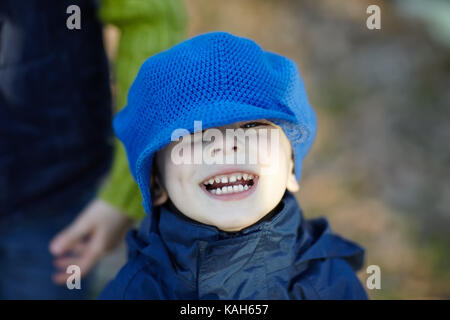Close-up portrait of funny little boy wearing a big blue hat in the autumn park Stock Photo