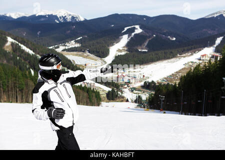 skier is standing on top of the mountain and points with his hand forward Stock Photo