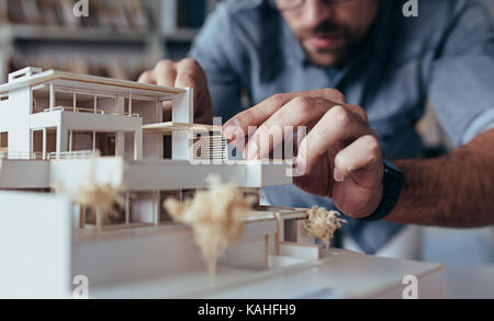 Close up of male architect hands making model house. Man architect working in the office. Stock Photo