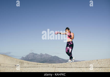 Fit young woman punching workout. Female boxer practicing boxing outdoors Stock Photo