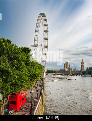 View over the Thames from Golden Jubilee Bridge, promenade with Ferris wheel London Eye, at the back Big Ben and Houses of Stock Photo