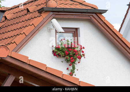 Cesky Krumlov, Czech Republic - August 17, 2017:Camera installed on a wall of a home with a small window and flowers Stock Photo