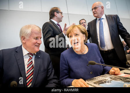 Berlin, Germany. 26th Sep, 2017. German Chancellor Angela Merkel (CDU) speaks with Bavaria's Premier Horst Seehofer (CSU) before the beginning of the first faction meeting of the Christian Democratic Union (CDU) and Christian Social Union (CSU) for the 19th legaslative period at the Bundestag in Berlin, Germany, 26 September 2017. The newly elected CSU state group leader Alexander Dobrindt (L) and faction leader Volker Kauder (R) speak in the background. Credit: Michael Kappeler/dpa/Alamy Live News Stock Photo