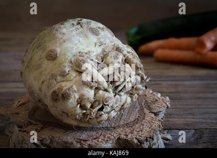 Raw celeriac radish on cork base and various vegetable on background Stock Photo