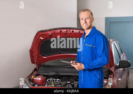 Smiling Young Mechanic Using Digital Tablet In Garage Stock Photo
