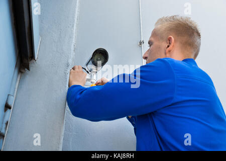 Close-up Of A Young Technician Installing Camera In Building Corner Stock Photo