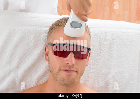 Beautician Giving Laser Epilation Treatment On Young Man Stock Photo