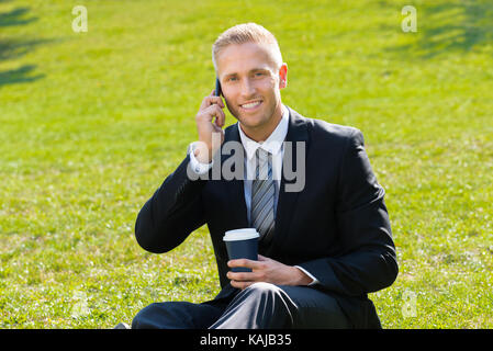 Young Smiling Man Holding Disposal Cup In Hand Talking On Cellphone Stock Photo
