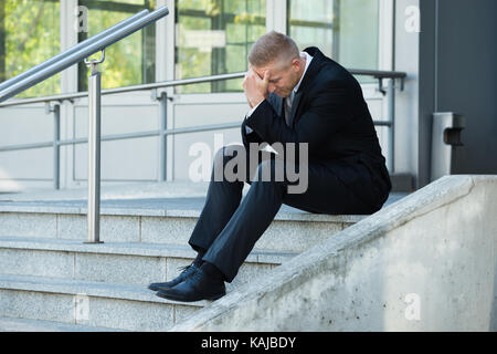 Portrait Of A Depressed Businessman Sitting On Stairs Stock Photo