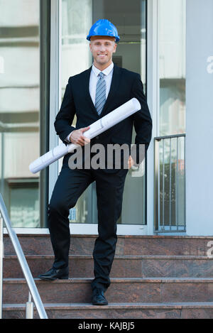 Smiling Young Architect Holding Blueprint In His Hand Stock Photo